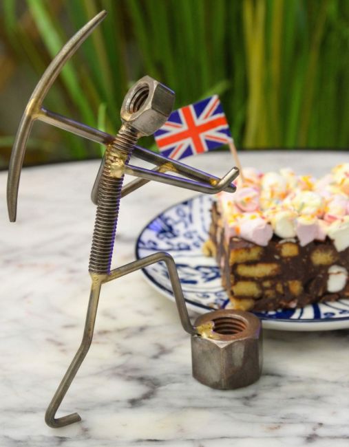 "Miner" Upcycled Metal Home Ornament holding pickaxe in front of cake