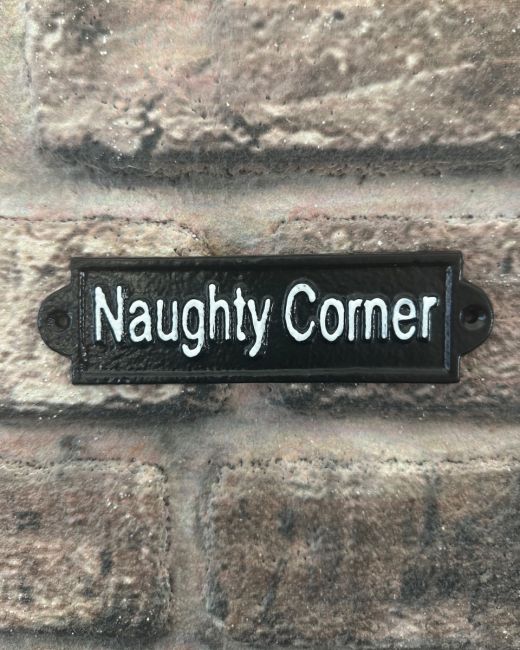 "Naughty Corner" Traditional Cast Iron Wall Sign mounted on a brick wall