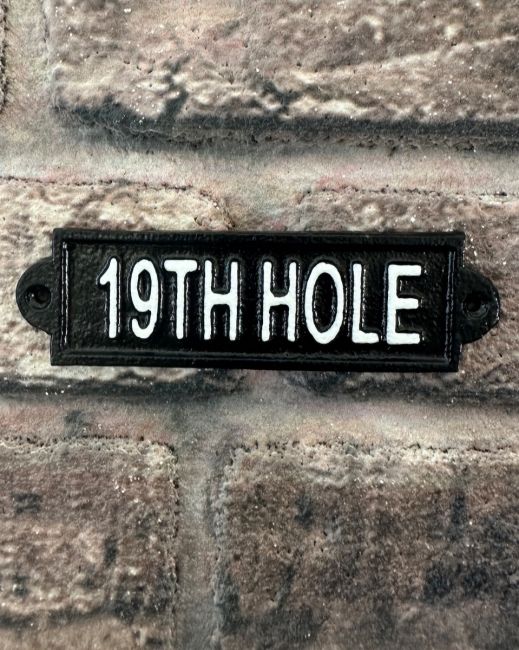"Nineteenth Hole" Traditional Cast Iron Wall Sign mounted on a brick wall