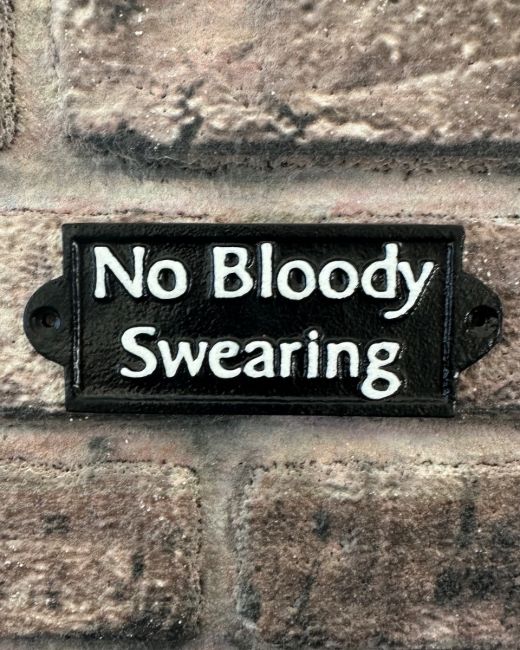 "No Bloody Swearing" Traditional Cast Iron Wall Sign mounted on a brick wall