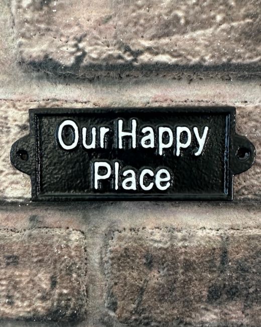 "Our Happy Place" Traditional Cast Iron Wall Sign mounted on a brick wall
