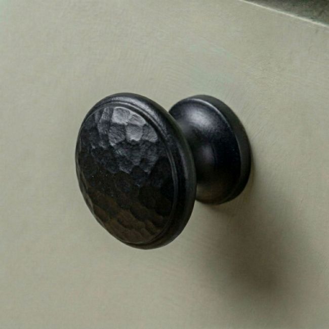 A 40mm Black Hammered Iron Cabinet Knob Placed on a Green Kitchen Cupboard - Digital Illustration 