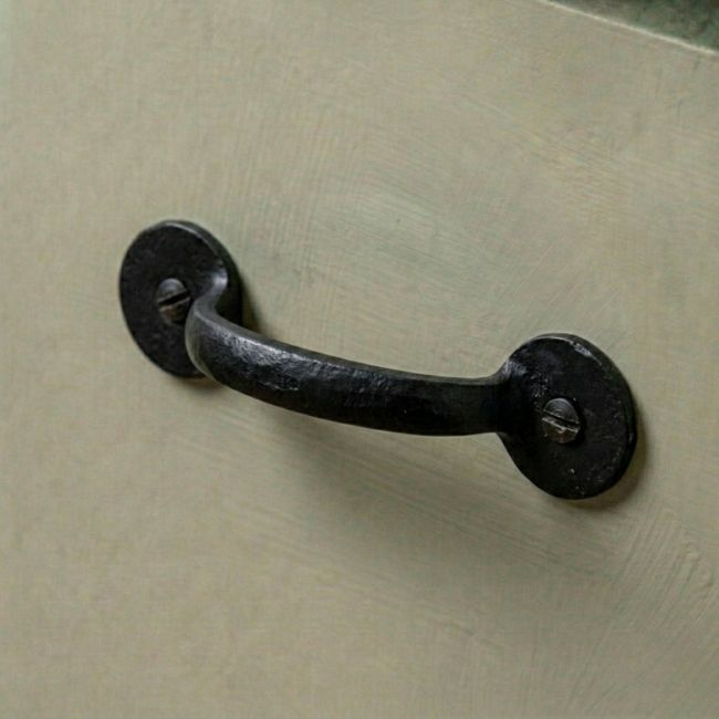 A Black Iron Round Plated Pull Handle Mounted on a Green Kitchen Cabinet - Digital Illustration 
