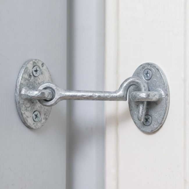 A Galvanised 3 Inch Cabin Hook Shown Up Close Holding a White Door - Digital Illustration