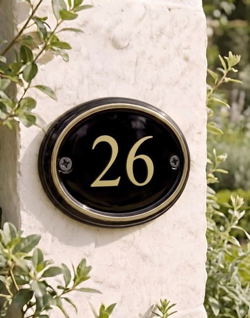 A Number 26 in Vinyl Polished Brass & Black Oval House Number Sign Mounted on a Sunny White Building Wall - Digital Illustration A Number 26 in Vinyl Polished Brass & Black Oval House Number Sign Mounted on a Sunny White Building Wall - Digital Illustration