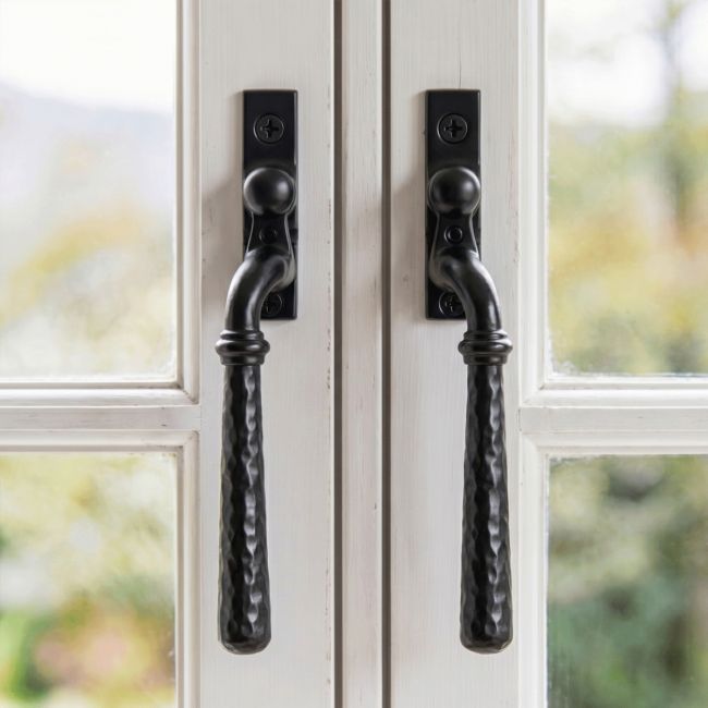 A Pair of 16mm Hammered Black Espagnolette Window Handles Fitted on a Traditional White Wooden Window Frame - Digital Illustration 