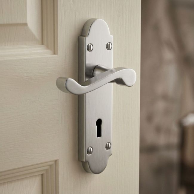 The Satin Chrome Arched Backplate Lock Handles - Victorian Scroll Keyhole Lever Pair on a White Background