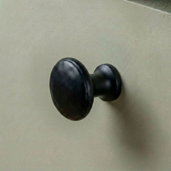 A Small Black Beaten Iron Cupboard Knob Mounted on a Contemporary Kitchen Cupboard Door - Digital Illustration