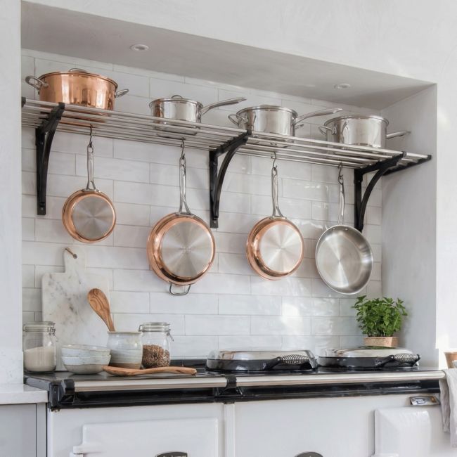 An Aga Inspired Stainless Steel Pot Rack Available in Various Sizes in a Tiled Kitchen Alcove Supporting Kitchen Utensils - Digital Illustration