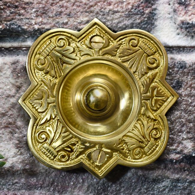 Polished Brass ornate bell push on brick wall Polished Brass ornate bell push on brick wall