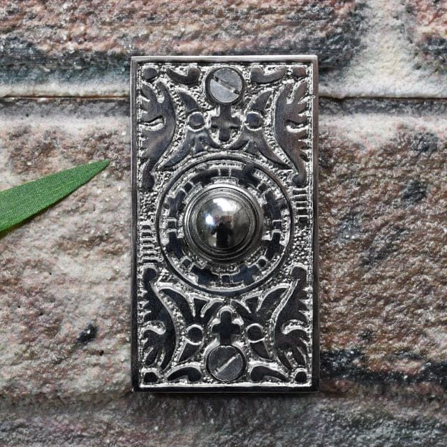 Bright chrome bell push on brick wall
