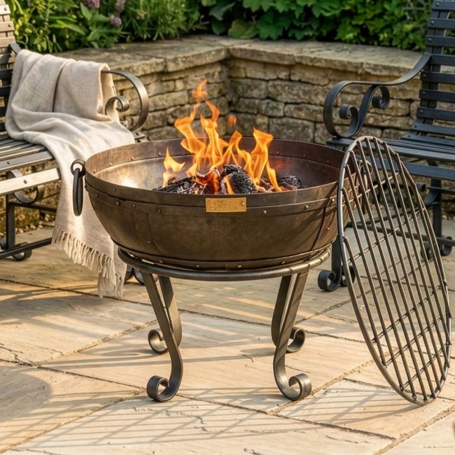 Digital Illustration of the 60cm Version of the Iron Kadai Bowl Fully Lit in Front of Rustic Garden Furniture