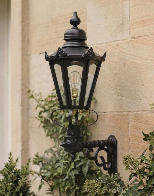 Digital illustration of the Medium Black Concordia Hexagonal Lantern on a Royale Bracket Mounted on a Traditional House Porch Wall