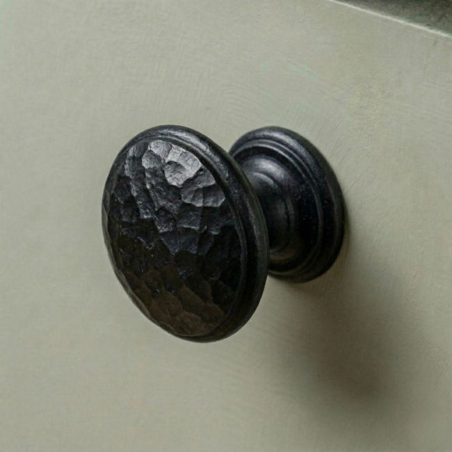 Digital Illustration of the Small Beeswax Beaten Iron Cupboard Knob Mounted on a Sage Green Cupboard