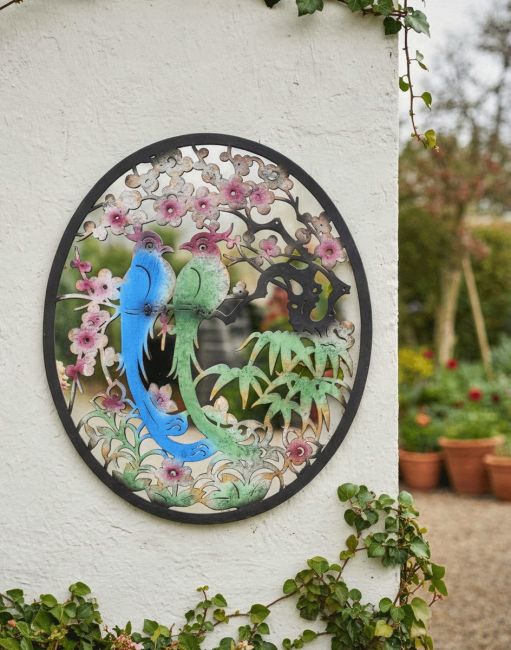 Digital Illustration of the Steel Cherry Blossom and Birds Mirrored Wall Art Mounted on a White Wall with Plant Pots in the Background