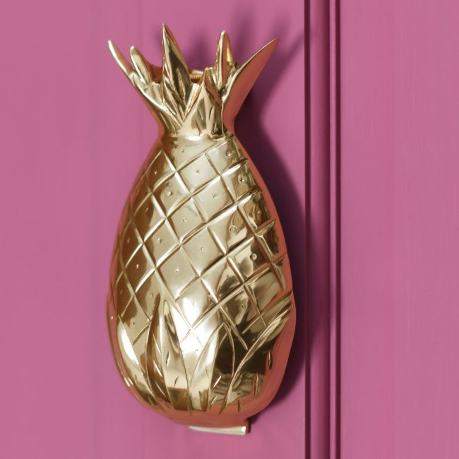 Polished brass pineapple door knocker on a pink door Polished brass pineapple door knocker on a pink door