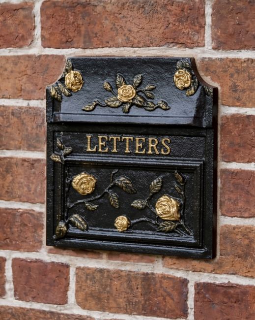 Ornate black and gold mailbox built into a wall