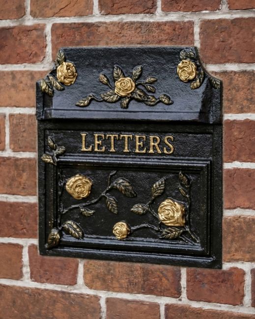Ornate black and gold mailbox built into a wall