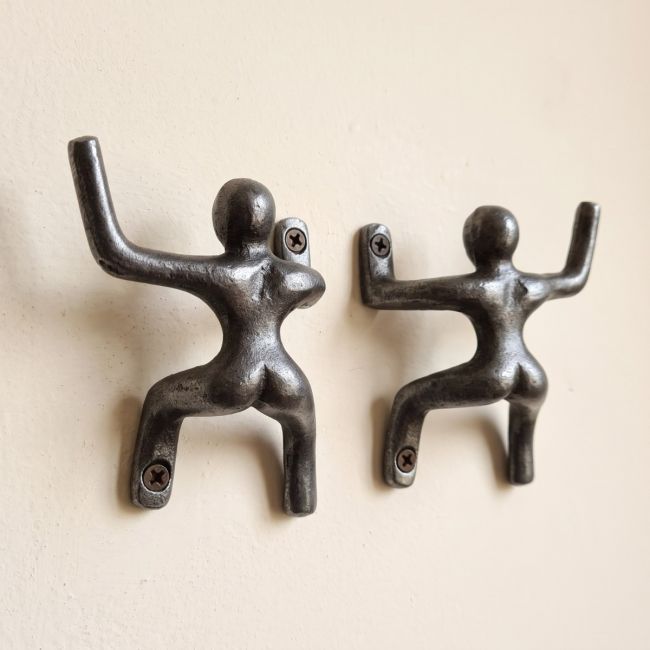 The 100mm Climbing Man Cast Antique Iron Coat Hook Pair Shown on a Magnolia Coloured Interior Wall - Digital Illustration