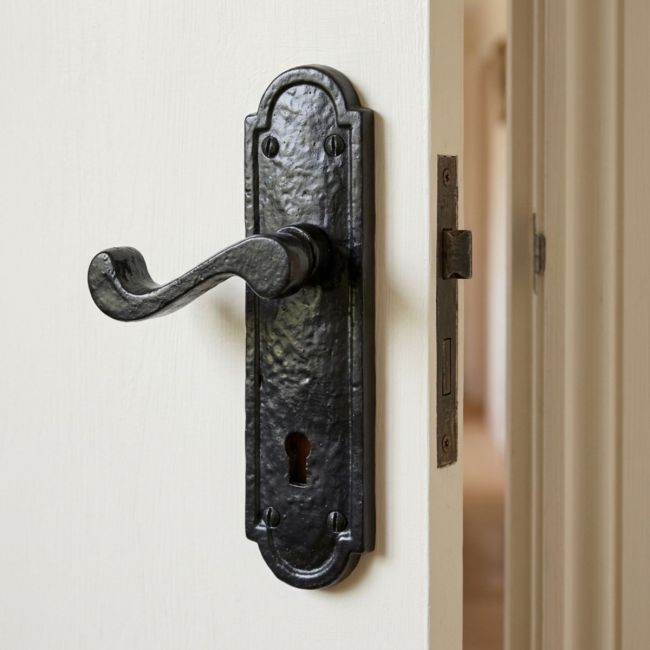 The Black Antique Arched Backplate Lock Handles - Rustic Scroll Keyhole Lever Pair on a White Background