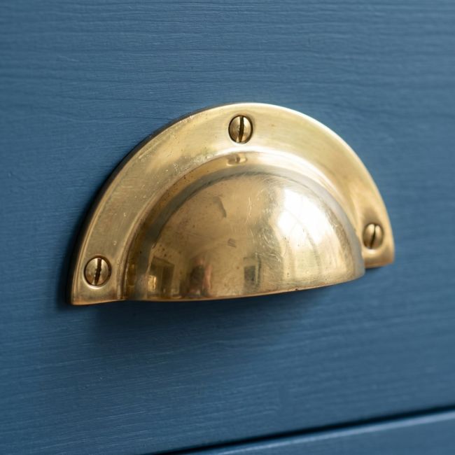 The Cotswold Round Lipped Cup Pull Handle in Brass Shown on a Blue Drawer - Digital Illustration