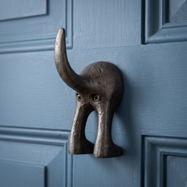 The Dog Tail Coat Hook in Cast Antique Iron - 115mm Mounted on a Blue Door Shown up Close - Digital Illustration