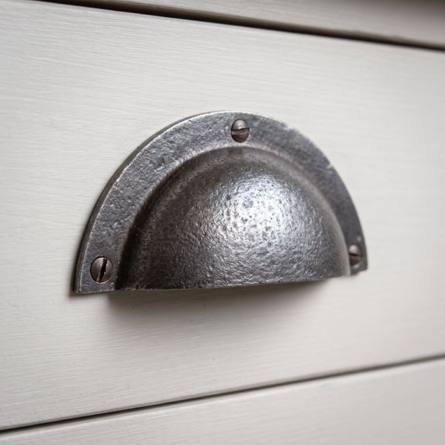The Half-Moon Cast Antique Iron Cup Pull Handle - 110mm Shown Close up on a Grey Drawer - Digital Illustration