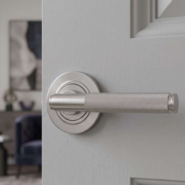 The Knurled Sprung Handle Set on a Round Rose in Satin Stainless Steel Shown at an Angle on a White Background