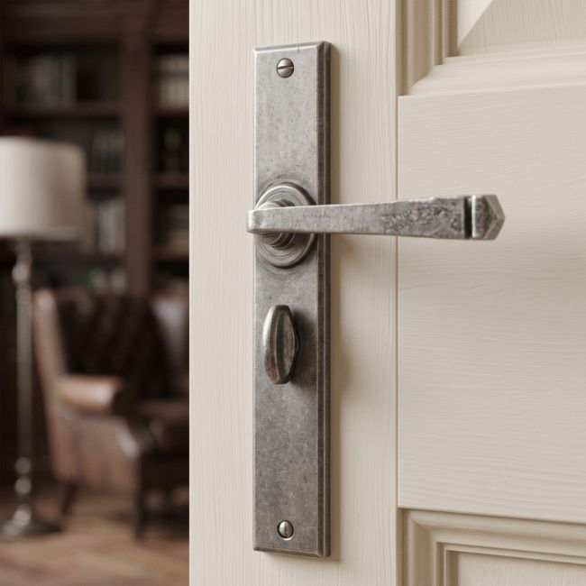 The Ravenscroft Large Pewter Simplistic Lever Handle With Bathroom Lock Shown Close up on a White Door in a modern Home - Digital Illustration