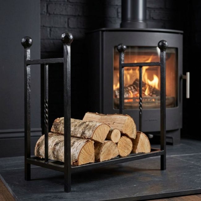 The Rectangular Fireside Log Holder with Ball Finials in Matt Black Next to a Modern Log Burner Stove - Digital Illustration