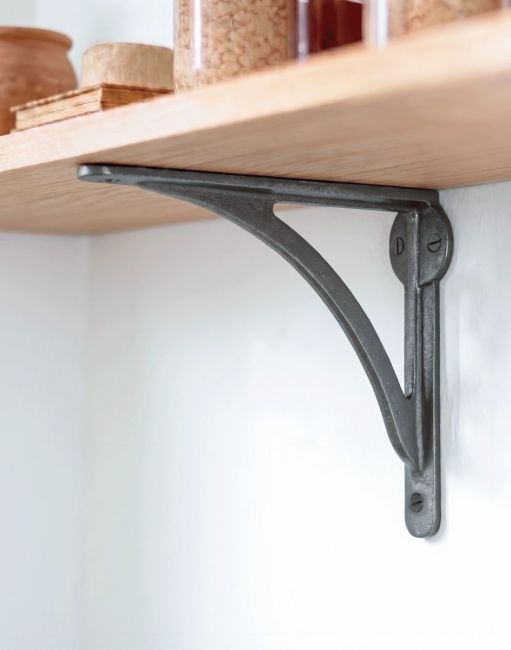 The 14 x 18cm Natural Iron Curved Shelf Bracket Mounted on a White Kitchen Wall in a Contemporary Home - Digital Illustration 