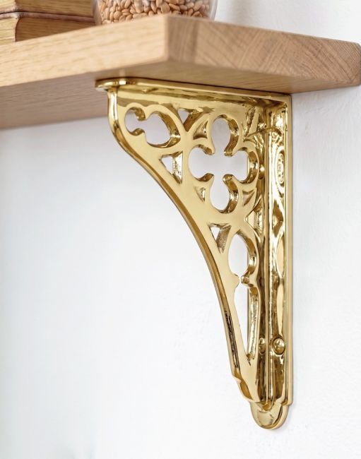 The 18 x 13cm Polished Brass Coalbrookdale Shelf Bracket Mounted on a White Interior Living Room Wall - Digital Illustration 