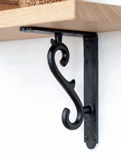 The 18 x 14cm Scroll Effect Wall Bracket in Cast Iron Mounted on a White Wall as Part of a Wooden DIY Shelf - Digital Illustration 