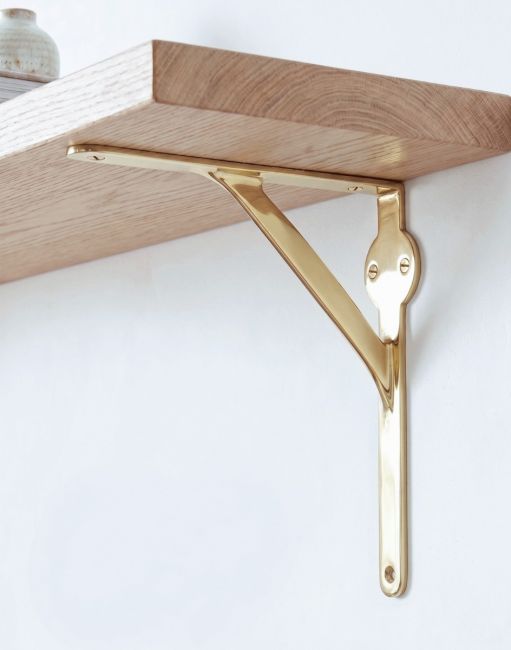 The 21 x 21cm Polished Brass Stylish Gallows Bracket Mounted on a Clean White Living Room Wall as A Wall Hanger - Digital Illustration 