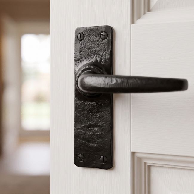 The "Bennett" Black Smooth Iron Lever Door Handle on a White Door in a Sunny Hallway - Digital Illustration