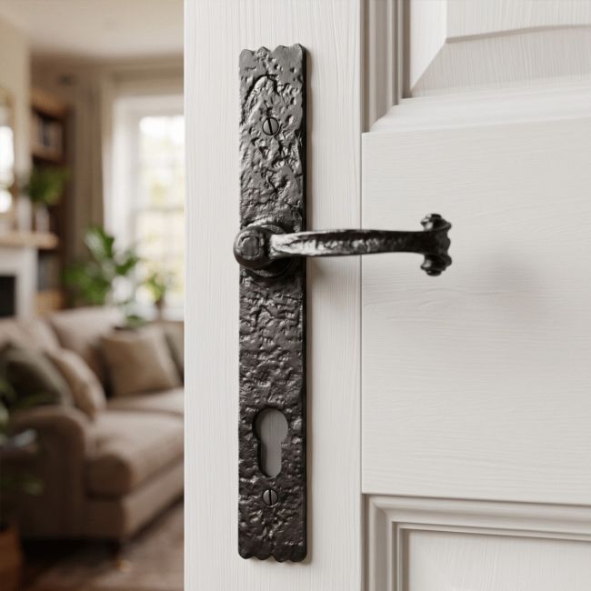 The "Farrington" Black Iron Long Profile Door Handle With Keyhole on a White Open Door Leading to a Living Room - Digital Illustration