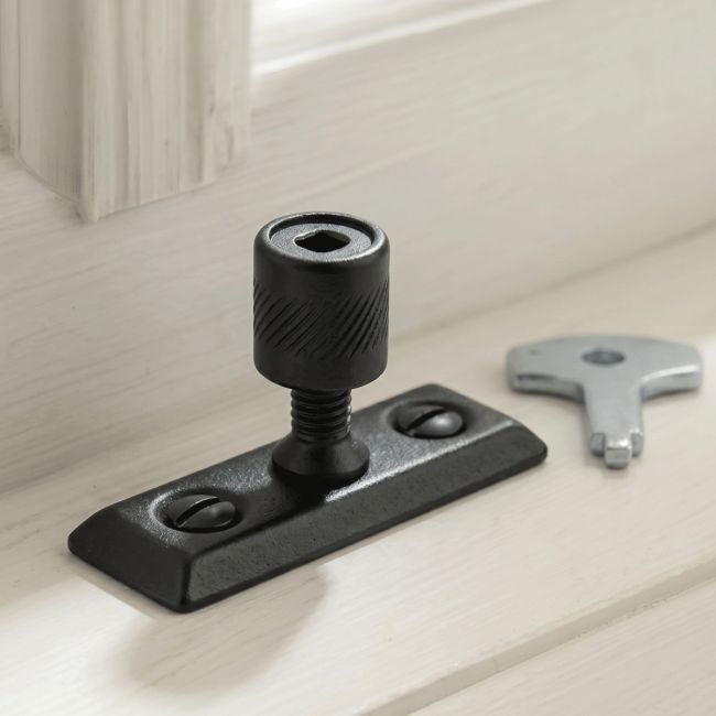 The "Harlington" Iron Locking Pivot Window Fastener Fitted in Front of a Wooden Window in a Modern Country Home - Digital Illustration