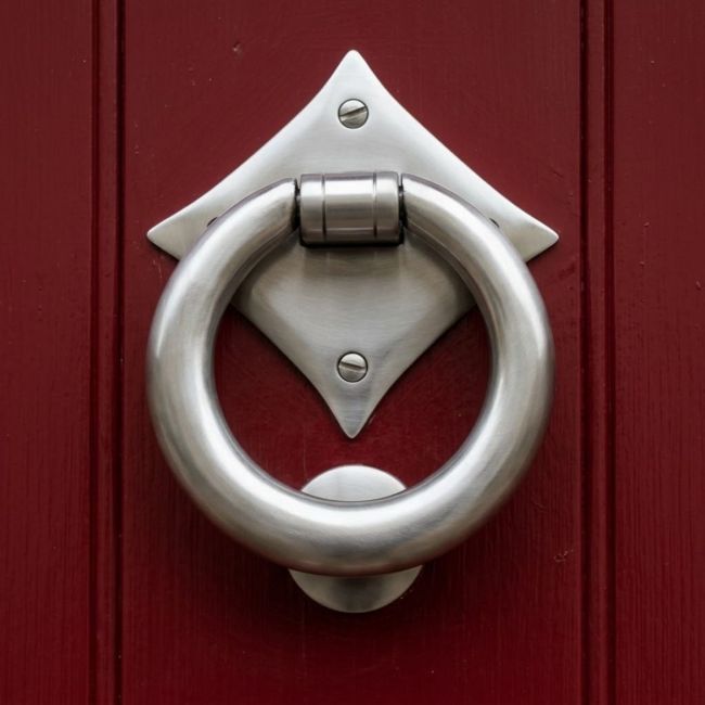 The "Lorien" Ring Door Knocker in Satin Stainless Steel Shown Front on Mounted to a Red Door - Digital Illustration