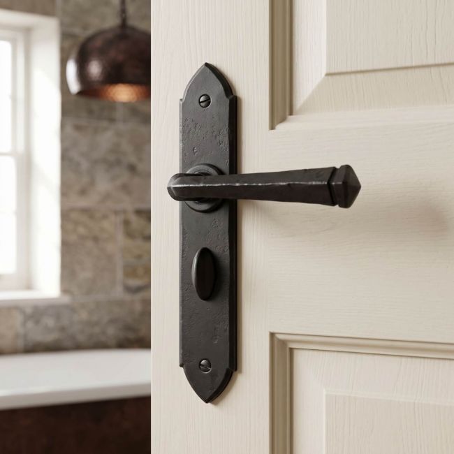 The "Orelia" Beeswax Square Iron Gothic Lever Handles and Bathroom Lock Shown on a White Door to a Modern Ensuite - Digital Illustration