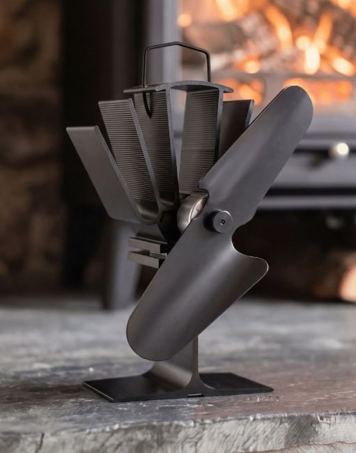 The 23.5cm Black Eco Wood Stove Fan in a Front of a cosy Log Burner Stove in a Country Home - Digital Illustration