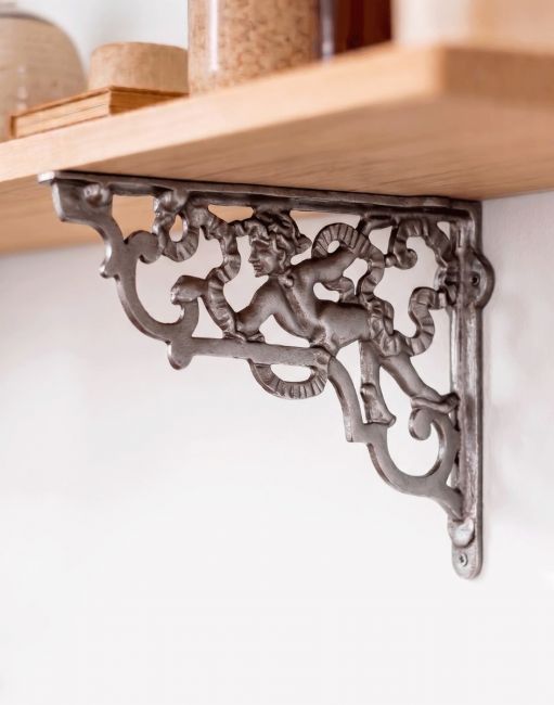 The 23 x 34cm Large Cherub Iron Shelf Bracket Mounted on a White Coloured Living Room Wall - Digital Illustration 