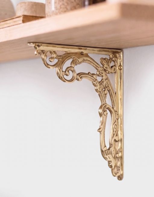 The 24cm x 19cm Ornate “Victorian Amalina” Scroll Bracket in Polished Brass Mounted on a Cream Coloured Living Room Wall - Digital Illustration
