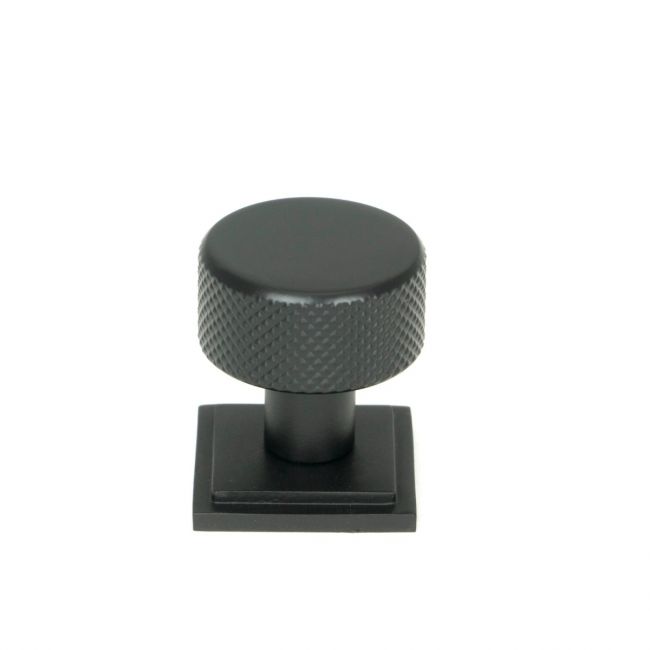 The 25mm Knurled Cabinet Knob on Square Rose in Matt Black Shown Upright on a White Background