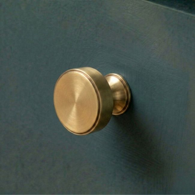 The 32mm "Atelier" Circular Cabinet Knob in Aged Brass on a White Background Shown Side on