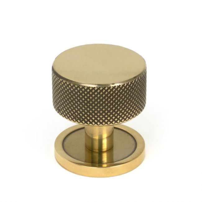 The 32mm Knurled Cabinet Knob on Plain Rose in Aged Brass Shown Upright on a White Background The 32mm Knurled Cabinet Knob on Plain Rose in Aged Brass Shown Upright on a White Background