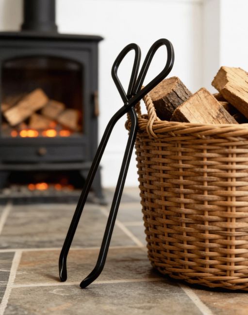 The 37cm Black Iron Fireplace Log Tongs on a Stone Tiled Floor Next to a Log Basket - Digital Illustration The 37cm Black Iron Fireplace Log Tongs on a Stone Tiled Floor Next to a Log Basket - Digital Illustration