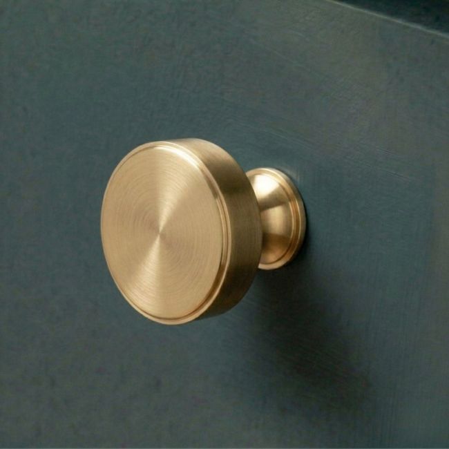 The 38mm "Atelier" Circular Cabinet Knob in Aged Brass on a White Background Shown Side On