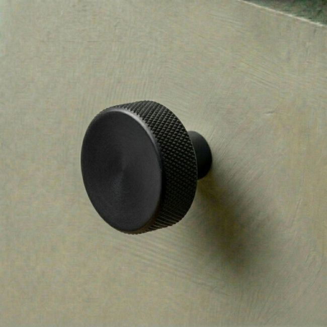 The 38mm "Vesper" Knurled Edge Cabinet Knob in Matt Black for Kitchen Cupboards on na Green Drawer - Digital Illustration
