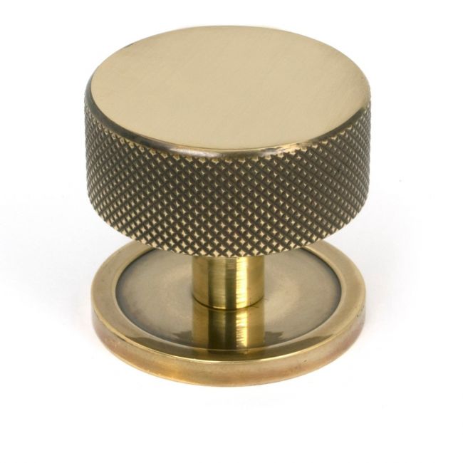 The 38mm Knurled Cabinet Knob on a Plain Rose in Aged Brass Shown Upright on a White Background The 38mm Knurled Cabinet Knob on a Plain Rose in Aged Brass Shown Upright on a White Background