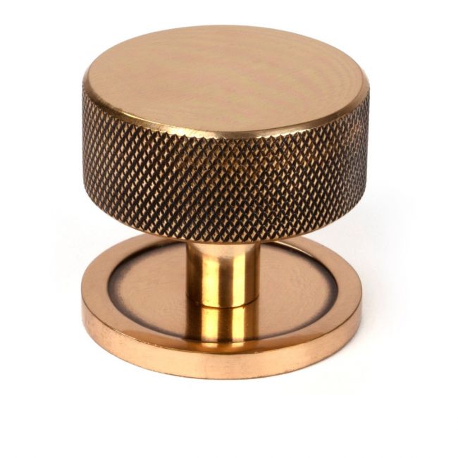 The 38mm Knurled Cabinet Knob on a Plain Rose in Polished Bronze Shown Upright on a White Background